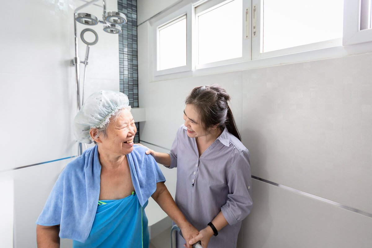 Caregiver helping older woman take a bath