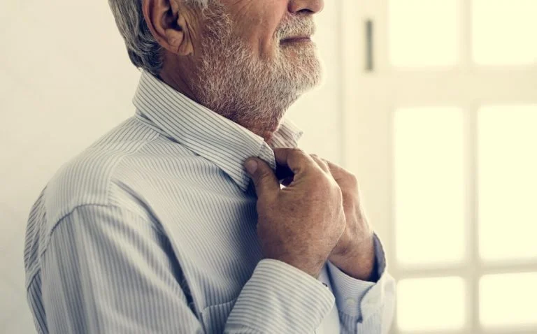 Older man dressing himself.