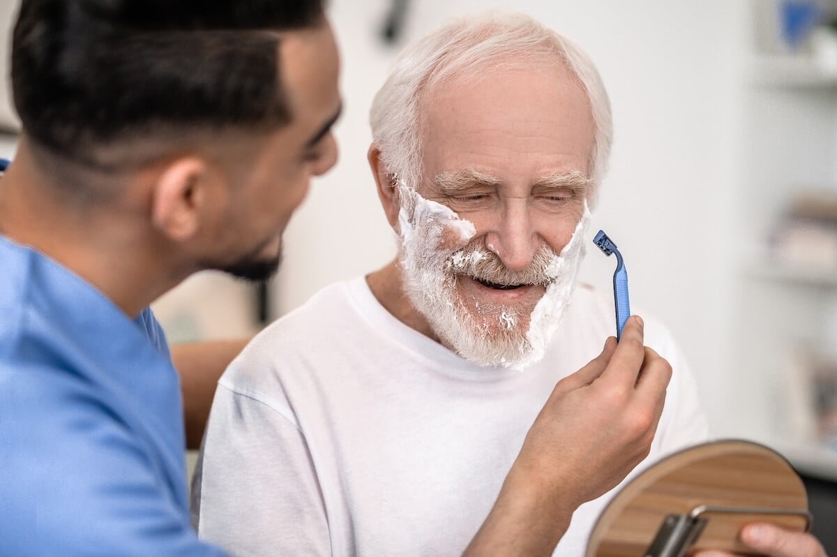 Caregiver helping a senior shave.