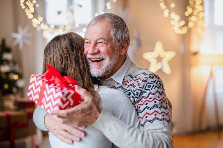 Older adult exchanging gifts with adult daughter.